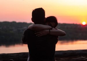 Due persone che si abbracciano al tramonto