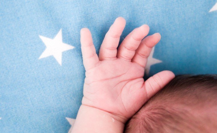 Babynamen von den Sternen - Hand von Baby vor blauem Sternenhintergrund