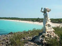 Escultura de mármol de una bruja en un entorno claro con la naturaleza y el mar