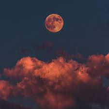 luna roja llena en un ambiente oscuro con nubes rojas