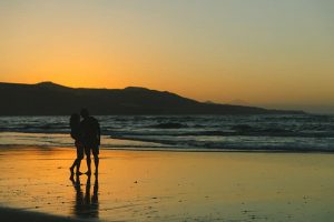 deux jeunes au loin profitant de leur amour au coucher du soleil