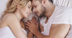 un couple très heureux est allongé sur le lit et se regarde avec amour