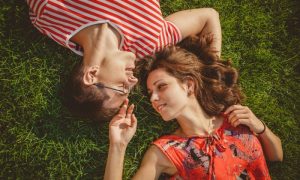 deux garçons amoureux sont allongés sur une pelouse verte et se regardent avec amour dans les yeux