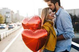 un couple se serre dans ses bras avec des ballons en forme de coeur